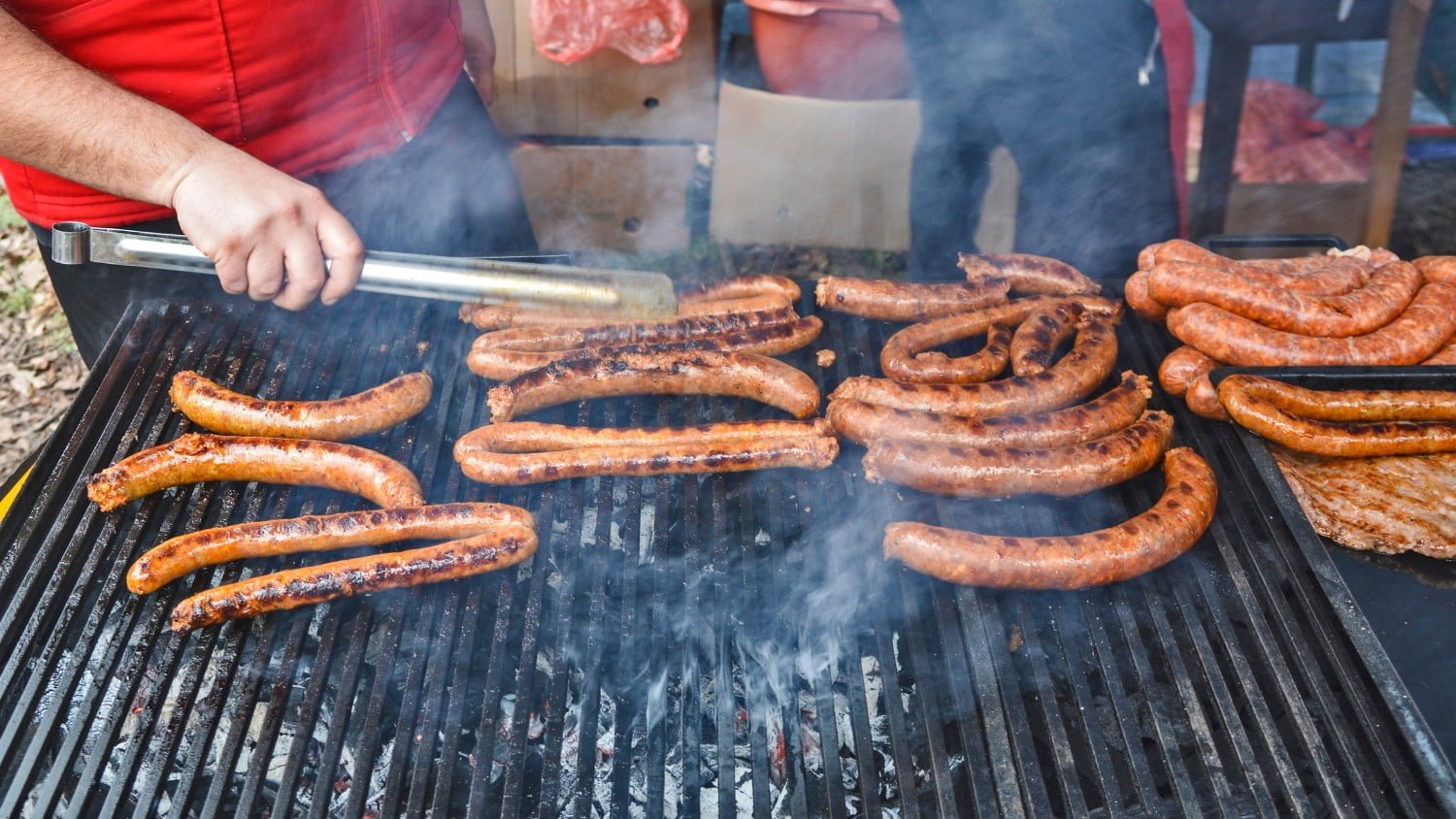 A man cooking bratwurst on a grill