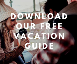 Couple looking at a map and drinking coffee with overlaying text saying "download our free Vacation Guide"