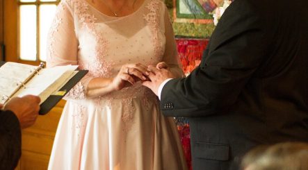 a wedding ceremony held at Hideaway Country Inn- the moment captured is when the bride is placing the ring on the groom's finger